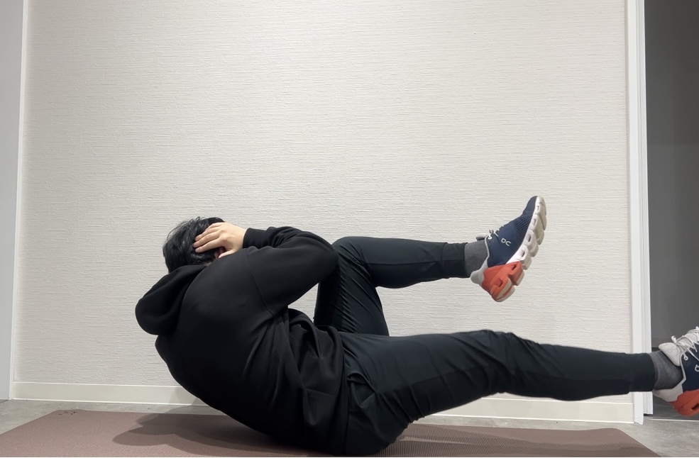 腹筋トレーニングの1つ「ツイストクランチ」をしているトレーナー