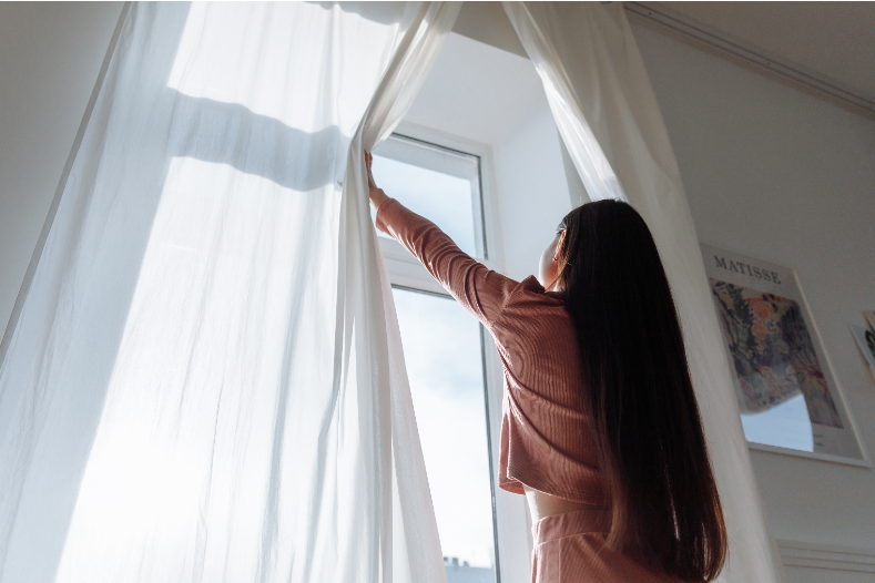 カーテンを開ける女性